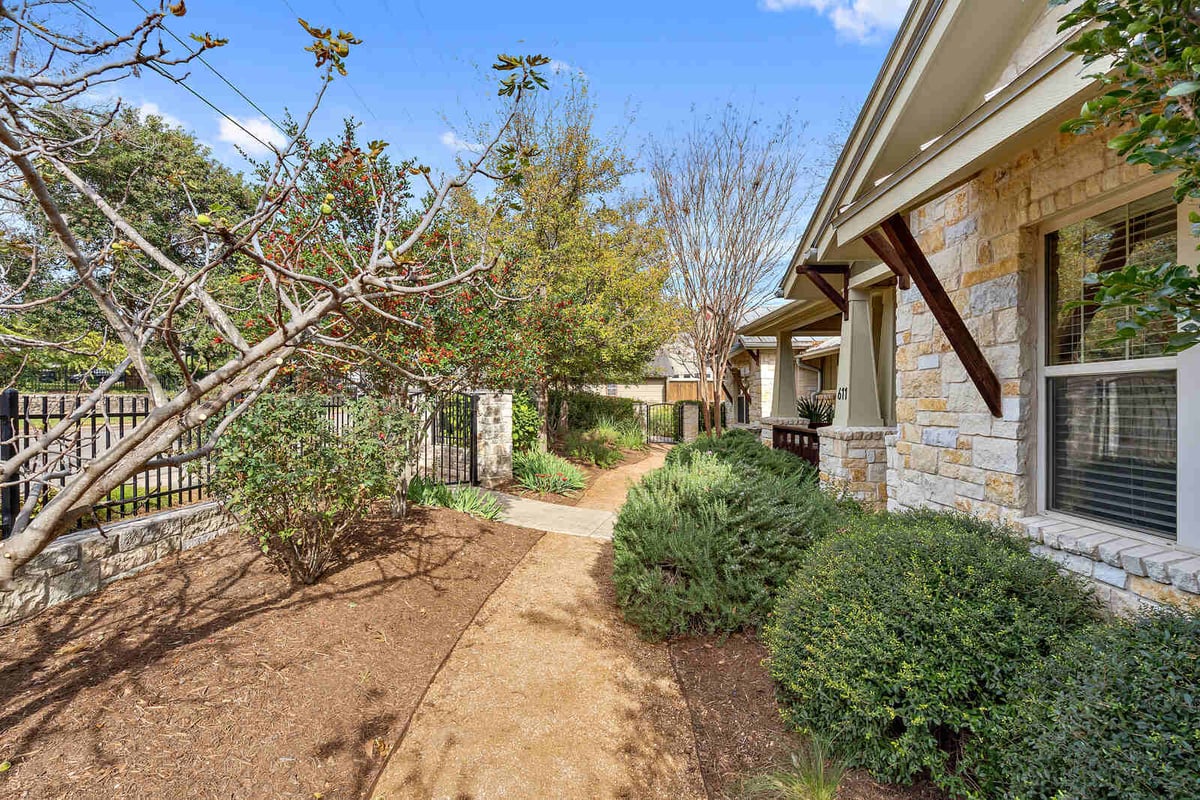 Side view of a custom home with stone exterior and lush landscaping, J Bryant Boyd in Georgetown, TX