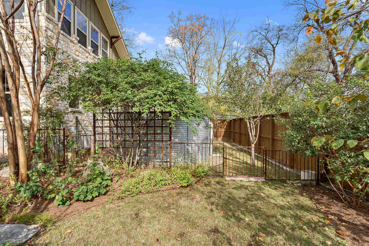 Side view of a custom stone home with trellis and natural greenery by J Bryant Boyd in Georgetown, TX