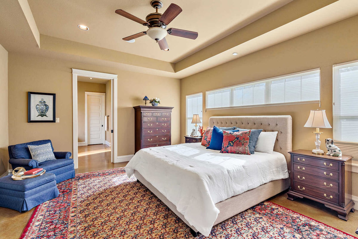 Spacious master bedroom with plush carpet and ceiling fan in a custom home by J Bryant Boyd in Georgetown, TX