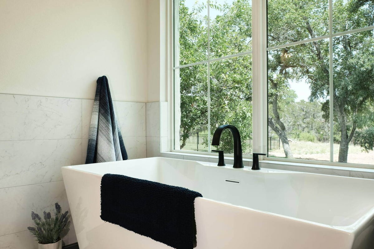 Freestanding bathtub by a large window in a custom home by J Bryant Boyd in Georgetown, Texas