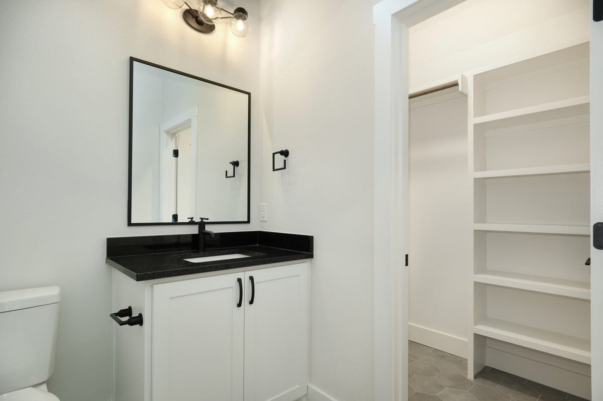 Modern bathroom with black countertop and white cabinetry by J Bryant Boyd in Georgetown, Texas