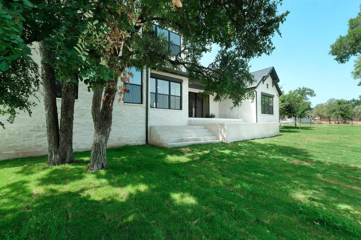 Side view of a custom home with green lawn by J Bryant Boyd in Georgetown, Texas