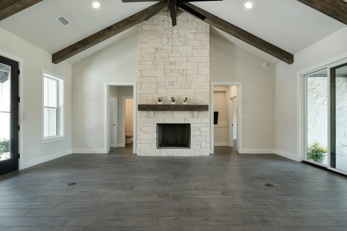 Spacious living room with stone fireplace in a custom home by J Bryant Boyd in Georgetown, Texas