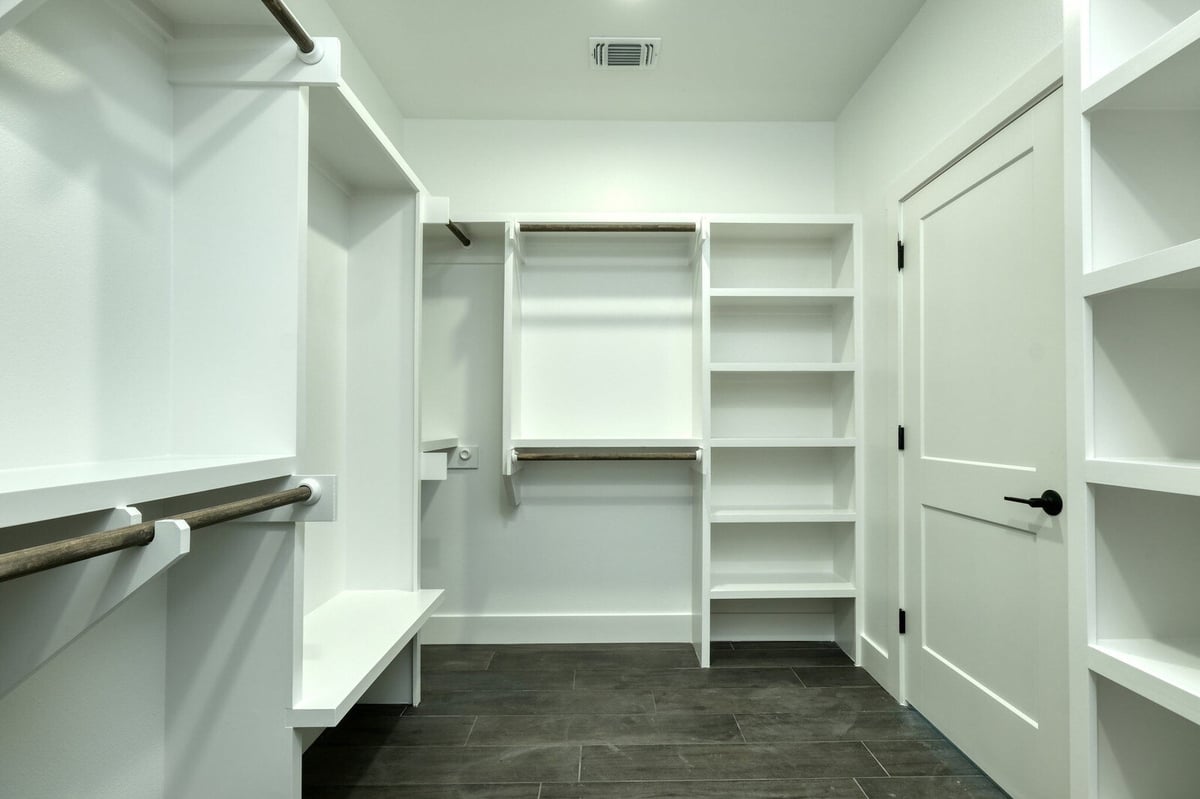 Walk-in closet with ample shelving and hanging space by J Bryant Boyd in Georgetown, Texas