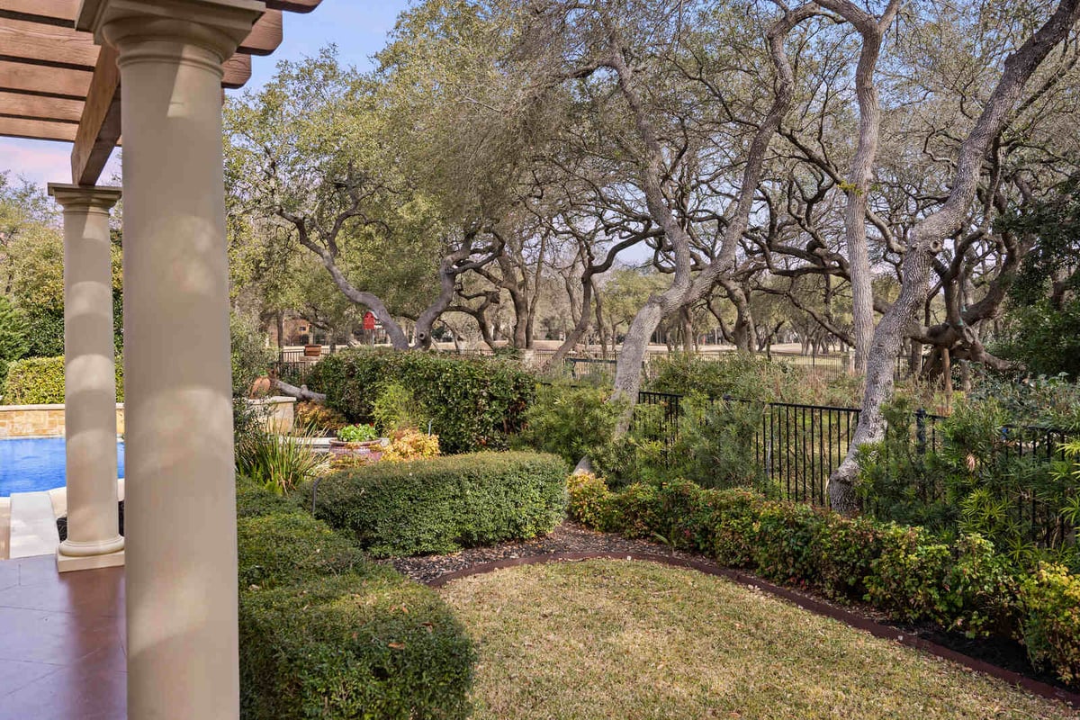 Backyard patio with garden and pergola, leading to a pool in a custom home by J Bryant Boyd, Georgetown TX