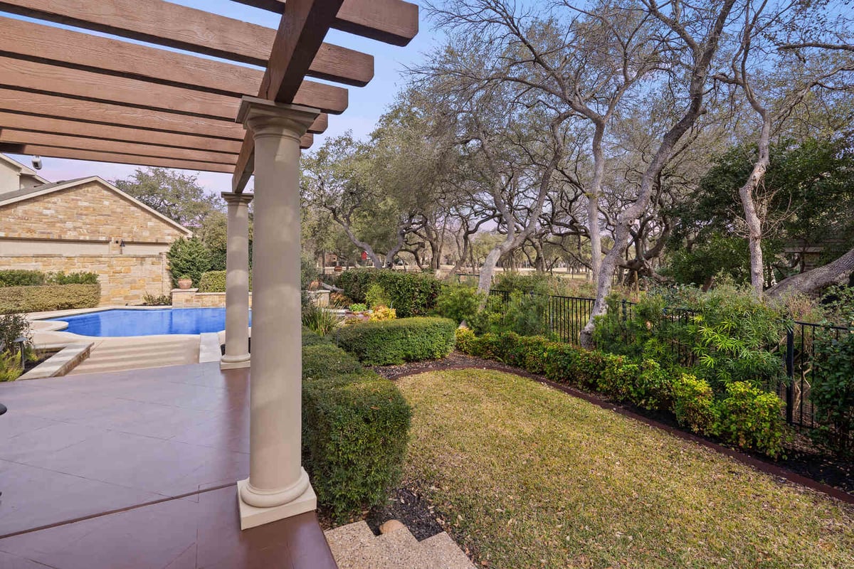 Backyard patio with pergola and pool, overlooking a lush landscape in a custom home by J Bryant Boyd, Georgetown TX-1