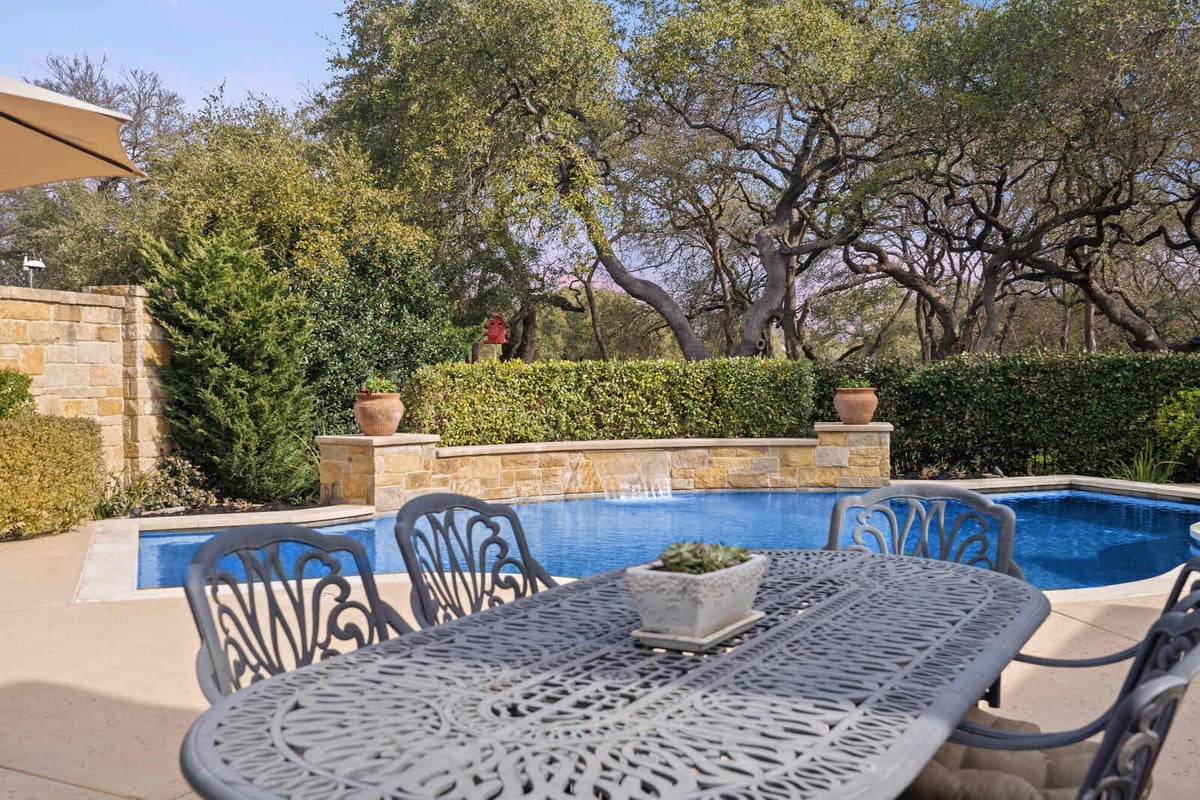 Backyard pool area with stone waterfall in a custom home by J Bryant Boyd, Georgetown, TX
