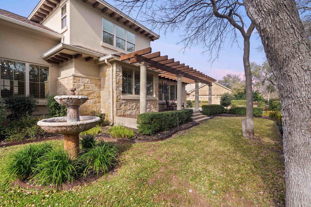 Backyard view of a custom home with pergola and stone exterior by J Bryant Boyd, Georgetown TX