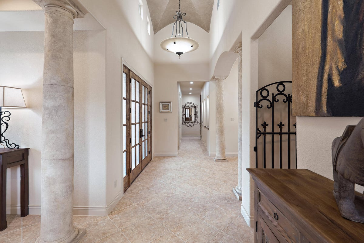 Bright hallway in a custom home by J Bryant Boyd in Georgetown, TX, with stone columns and a large chandelier-1