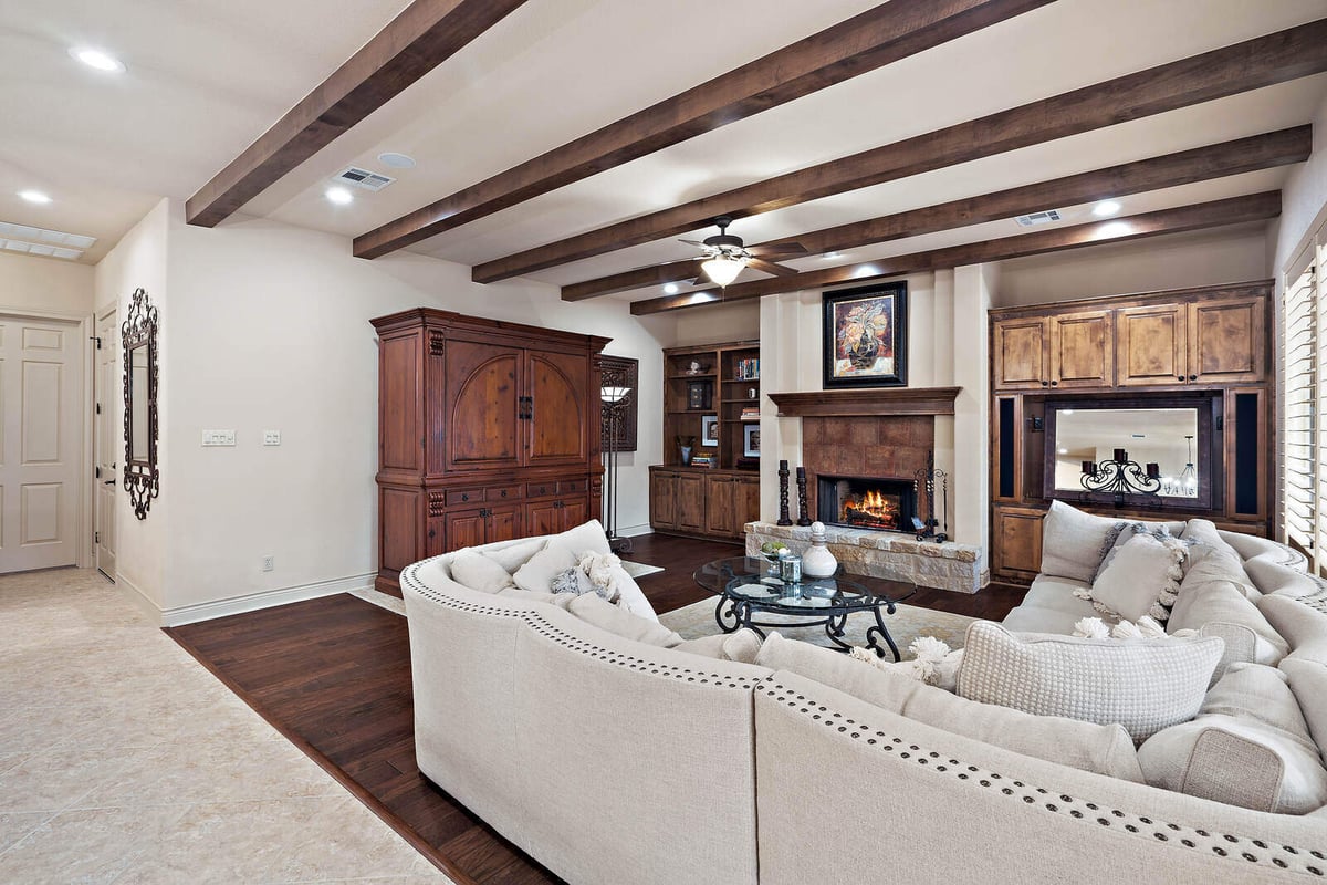 Cozy living room with fireplace and exposed wooden beams in a J Bryant Boyd custom home in Georgetown, TX