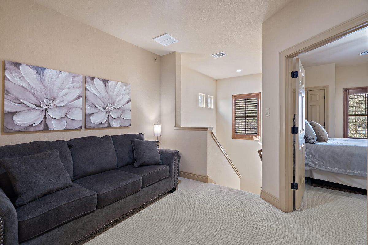 Cozy upstairs sitting area with gray sofa and floral artwork in a custom home by J Bryant Boyd, Georgetown TX-1