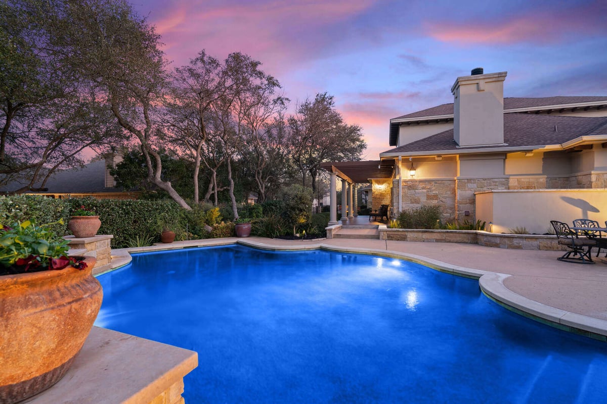 Custom home backyard pool glowing under a colorful evening sky by J Bryant Boyd, Georgetown, TX