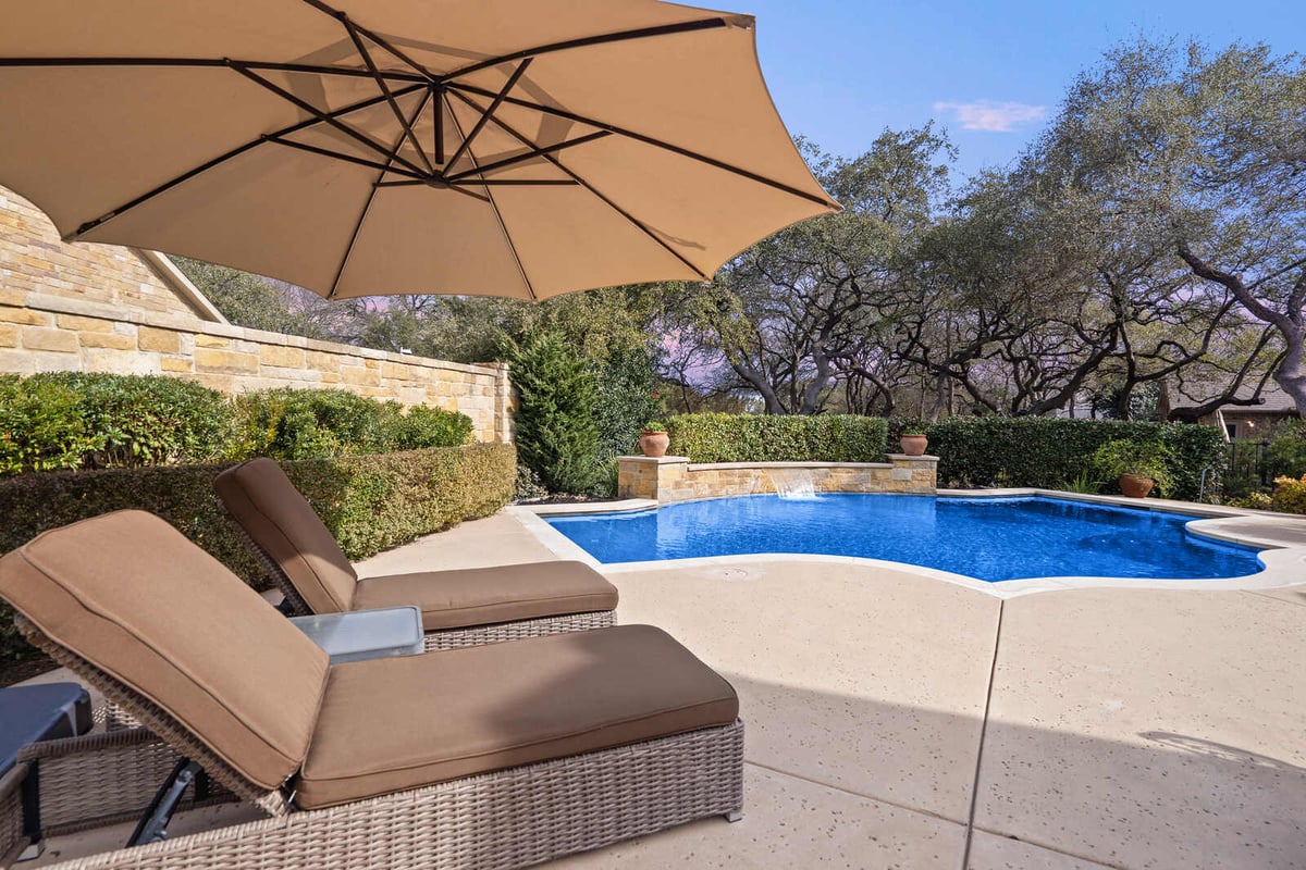 Custom home poolside view with lounge chairs and umbrella by J Bryant Boyd, Georgetown, TX