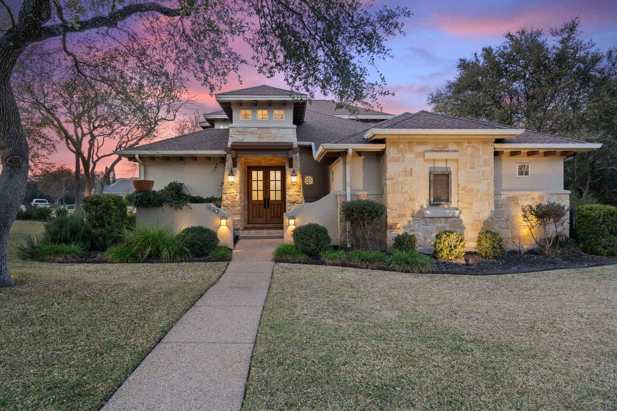 Custom stone home with wooden front door at sunset, built by J Bryant Boyd in Georgetown, TX-1