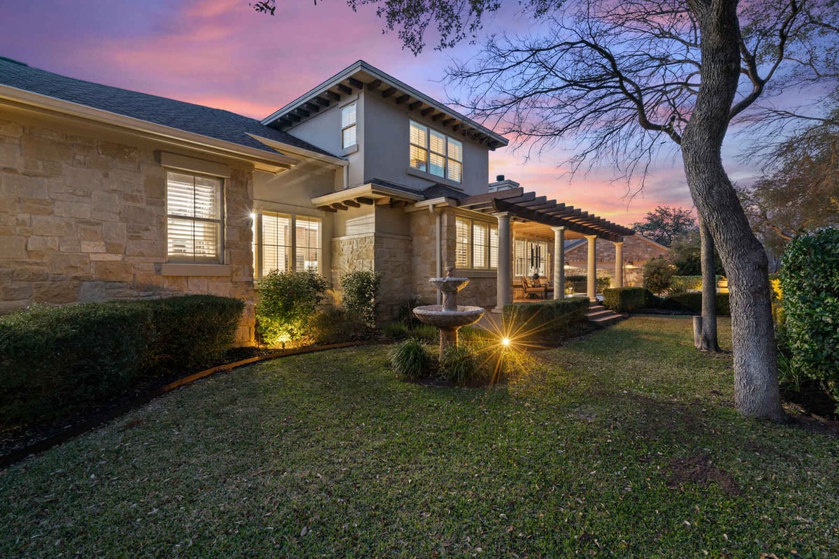 Daytime view of a custom stone home surrounded by mature trees in Georgetown, TX by J Bryant Boyd-1