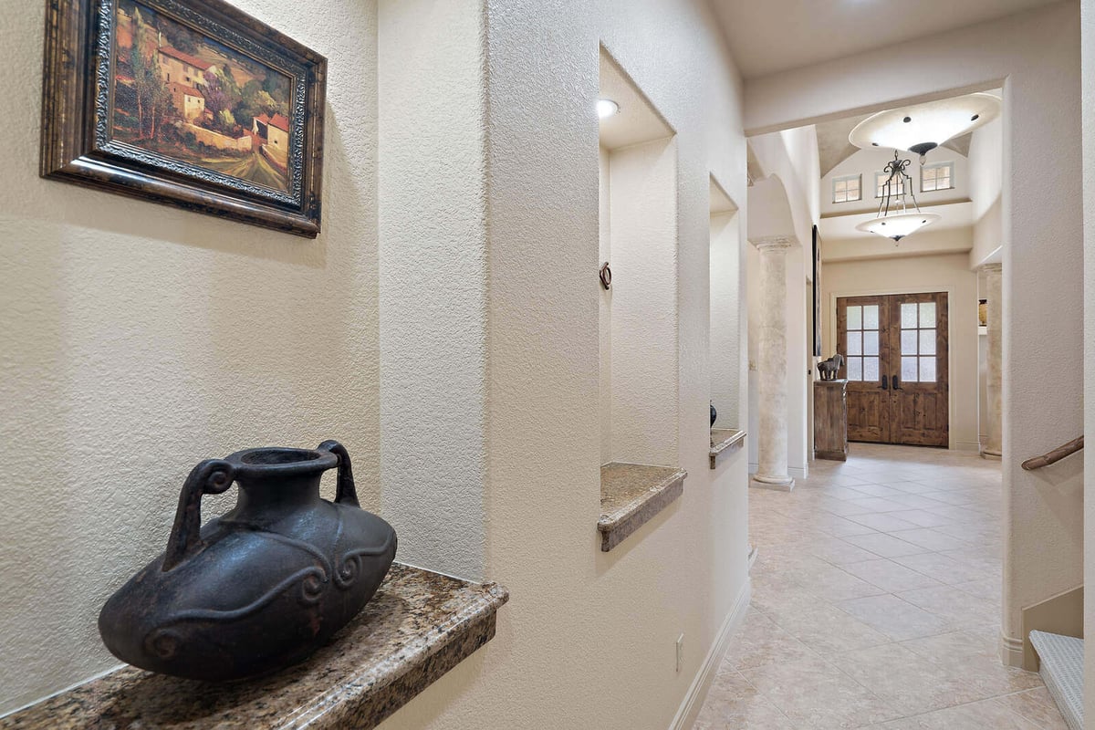 Detailed hallway in a custom home by J Bryant Boyd in Georgetown, TX, with decorative niches and a rustic vase