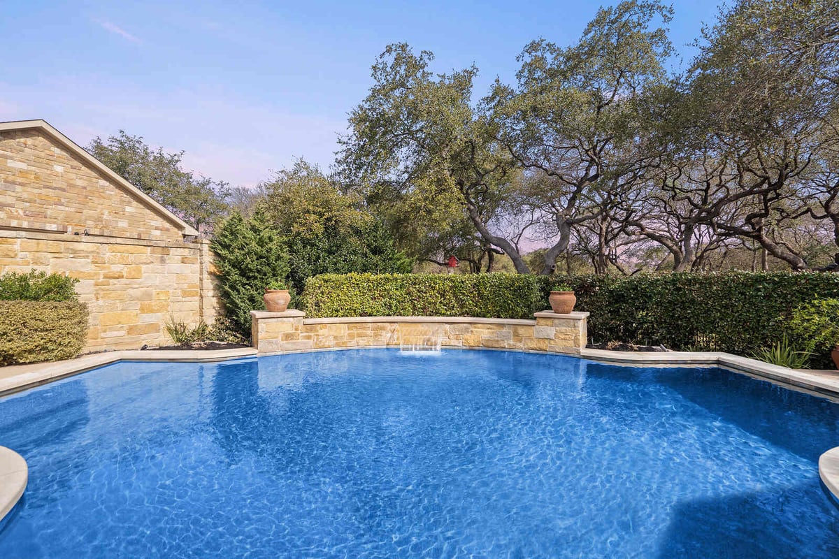 Elegant backyard with swimming pool and stone wall in a custom home by J Bryant Boyd, Georgetown TX