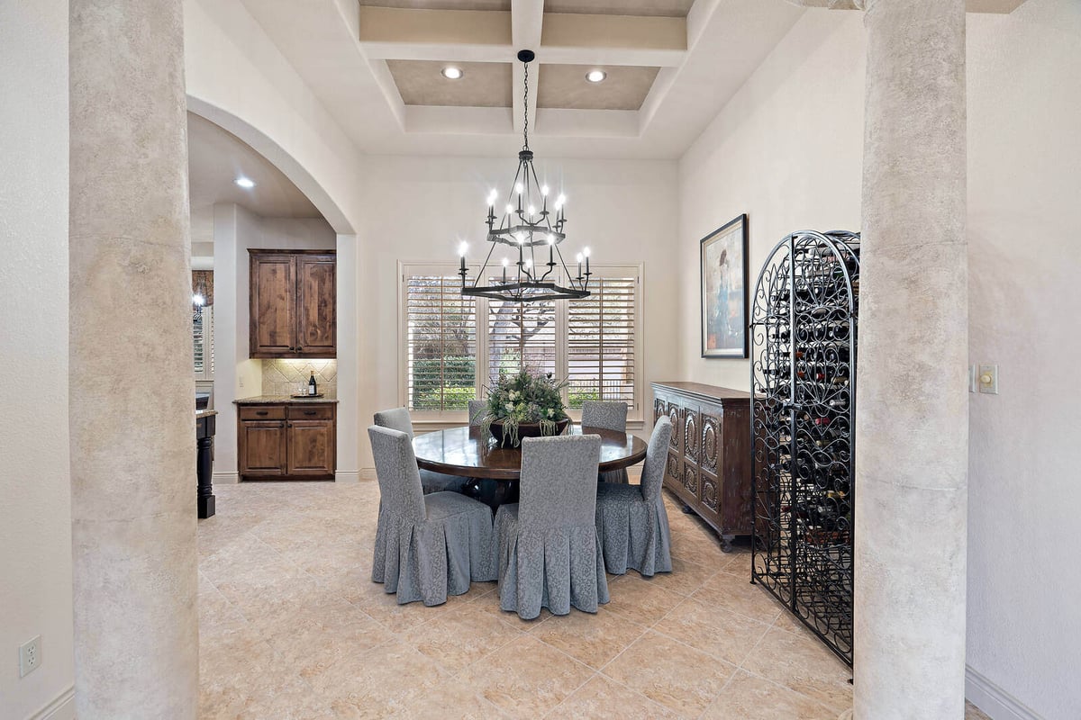 Elegant dining room with wine storage and chandelier in a J Bryant Boyd custom home in Georgetown, TX-1