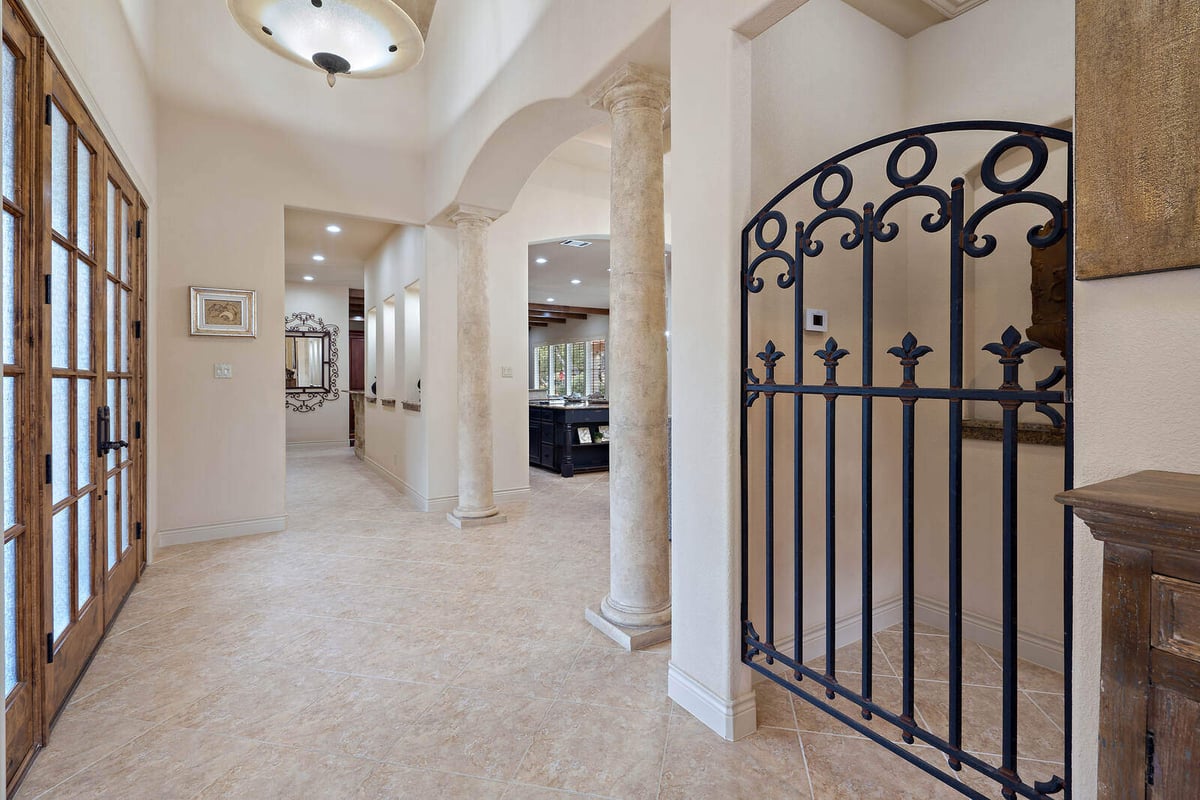 Elegant hallway in a custom home by J Bryant Boyd in Georgetown, TX, featuring stone columns and an iron gate-1