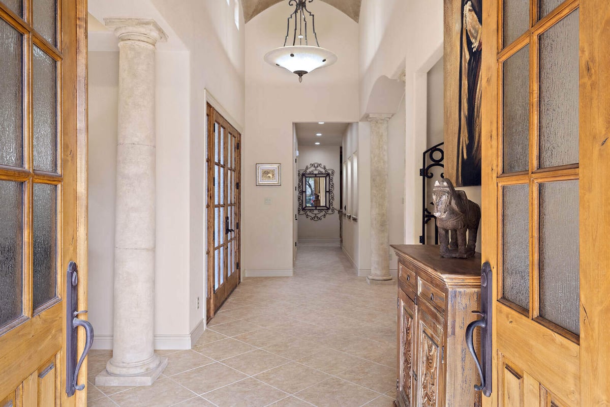 Elegant hallway in a custom home by J Bryant Boyd in Georgetown, TX, featuring stone columns and wooden doors