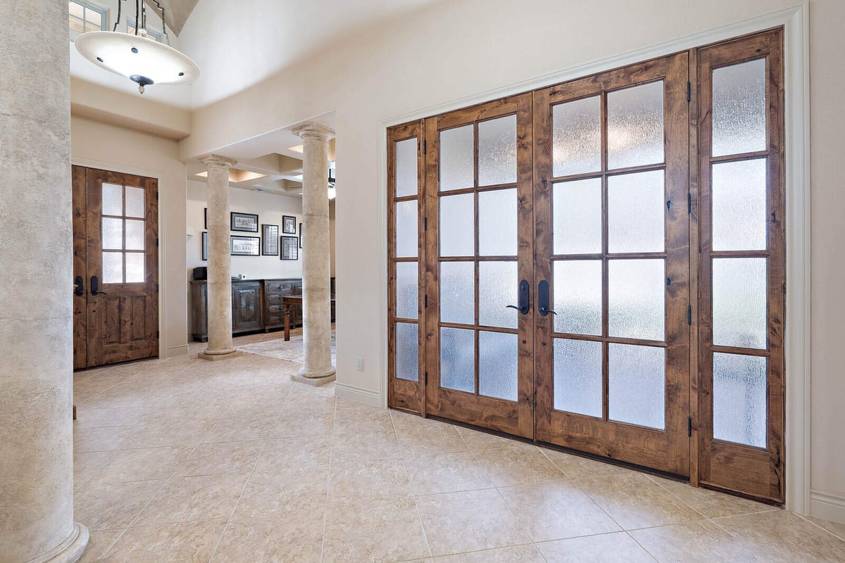 Entryway in a custom home by J Bryant Boyd in Georgetown, TX, with wooden double doors and a stone column-1