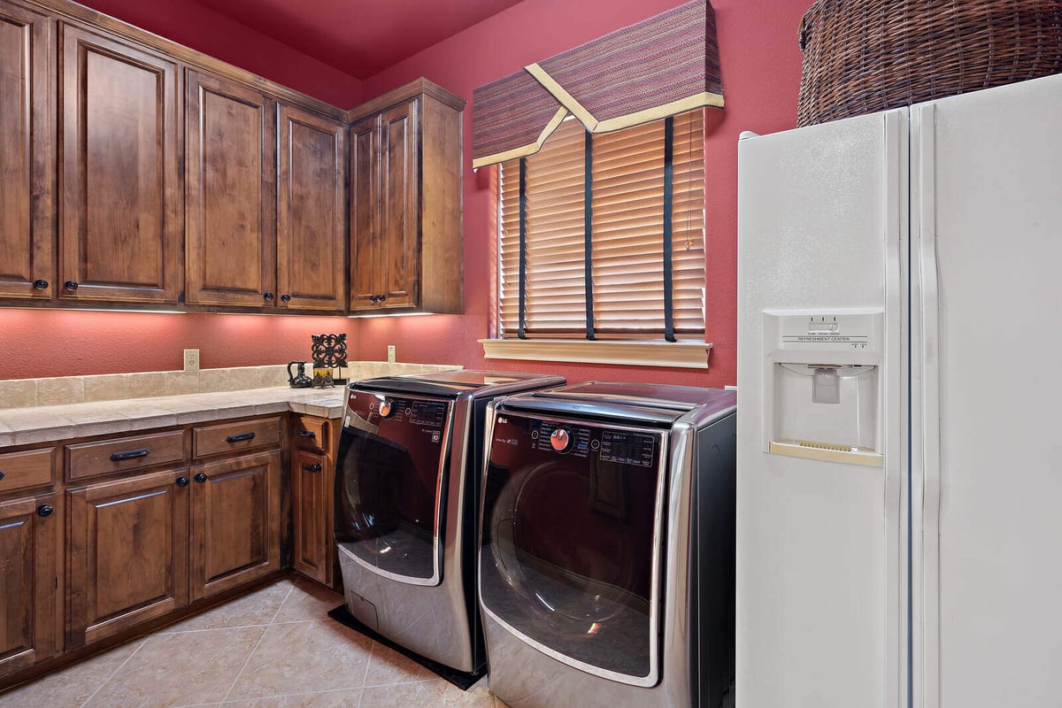 Warm-toned laundry room with wood cabinetry and modern appliances in a custom home by J Bryant Boyd, Georgetown TX