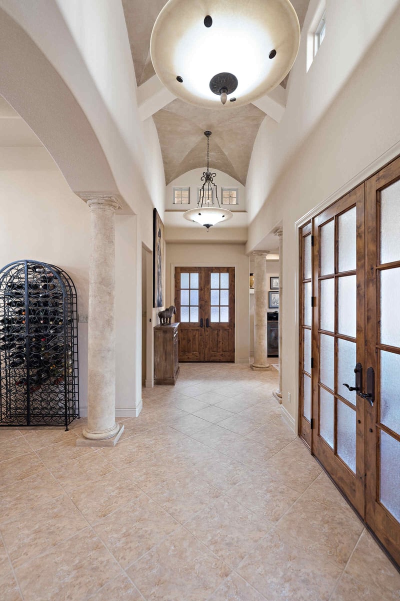 Welcoming hallway in a custom home by J Bryant Boyd in Georgetown, TX, featuring a grand chandelier and rustic decor